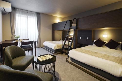 a hotel room with two beds and a desk at KURASHIKI Station HOTEL 和奏 in Kurashiki