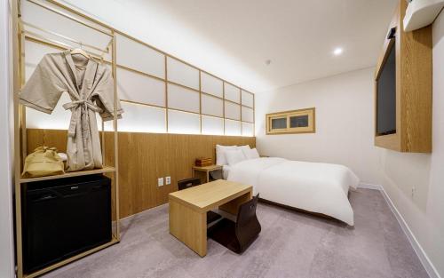a hotel room with a white bed and a table at Ryokan Hotel The Red Dragonfly in Incheon
