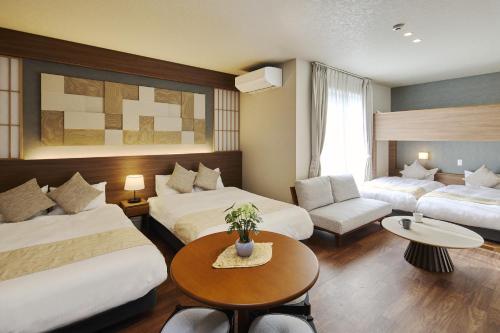 a hotel room with two beds and a table at KURASHIKI Station HOTEL 和奏 in Kurashiki