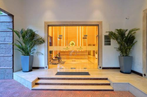 a lobby with two potted plants in front of a door at Hotel Le Jardin in Erode