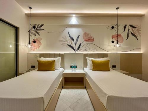 two beds in a room with flowers on the wall at Hotel Le Jardin in Erode