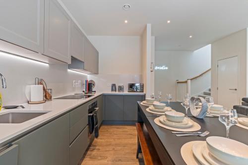 a kitchen with white cabinets and a long table with dishes at 3 Bed Duplex, Pool Table, 4 Stops to Wembley in Hatch End