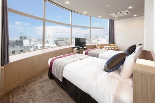 two beds in a hotel room with a large window at HOTEL MYSTAYS Tachikawa in Tachikawa