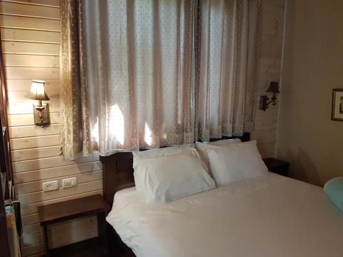 a bed with white pillows in a bedroom with a window at Betzel Ha'Ella in Kahal