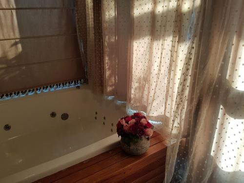 a vase of flowers sitting next to a bath tub at Betzel Ha'Ella in Kahal