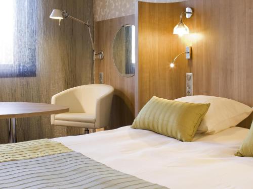 ein Hotelzimmer mit einem Bett, einem Tisch und einem Stuhl in der Unterkunft Mercure Angers Centre de Congrès in Angers