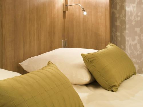 ein Bett mit zwei Kissen und einer Lampe darauf in der Unterkunft Mercure Angers Centre de Congrès in Angers