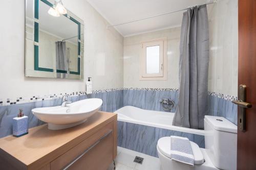 a bathroom with a sink and a tub and a toilet at Villa Eudora in Tsoukalades