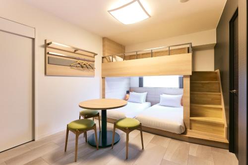 a bedroom with a bunk bed and a table and chairs at Karaksa Hotel Osaka Namba in Osaka