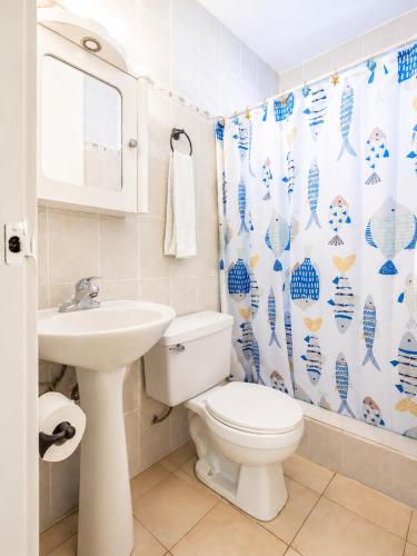 a bathroom with a toilet and a sink and a shower curtain at 30 seconds beach aparment in Aguacate