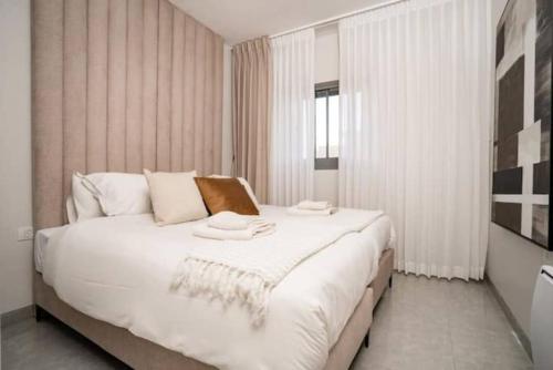 a bedroom with a large white bed with towels on it at 1 Br Apartment In Shaul Adler in Jerusalem