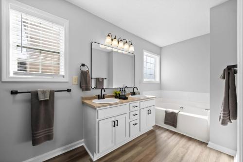 a bathroom with a sink and a mirror and a tub at Hollywood Hideaway in Clarksville