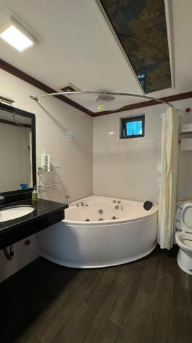 a large white bath tub in a bathroom with a toilet at Sakura building hotel & restaurand in Hải Dương