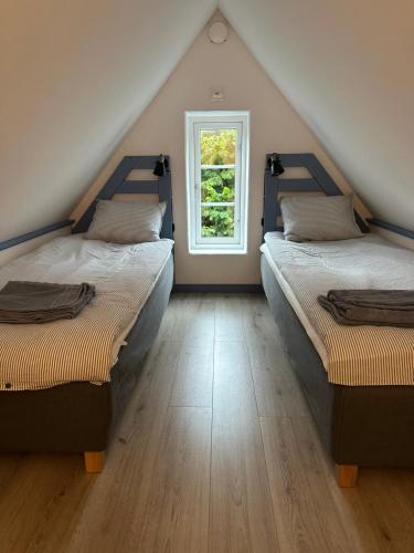two beds in a attic room with a window at Charmig stuga i Abbekås in Abbekås