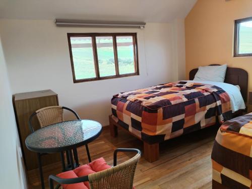 a bedroom with a bed and a table and chairs at Apu Tacllo lodge in Layo