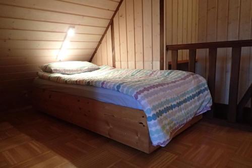 Cama en habitación con pared de madera en vakantiehuis Hunsrück, en Leisel