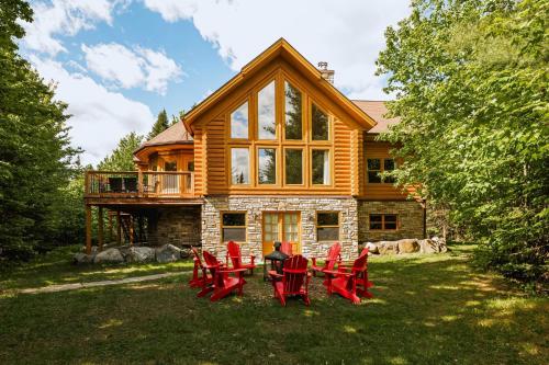 a group of red chairs in front of a log cabin at Fiddler Lake Resort - Deer 47 in Mille-Isles