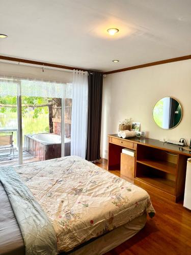a bedroom with a bed and a desk and a window at Ban Mali Cafe & Riverside Stay in Ban Chang