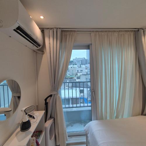 a hotel room with a bed and a large window at Stay in Seoul, 3 min to Seoul Station, New Apt, 3 Air Conditioners, Elevator, Rooftop, Quiet & Cozy in Seoul