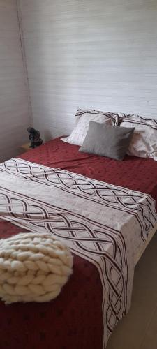 a bed with a red and white blanket on it at El Tropezon cabaña in Resistencia