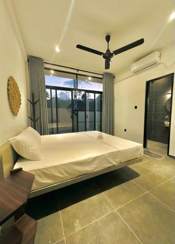 a bedroom with a large bed with a ceiling fan at The Elm in Weligama