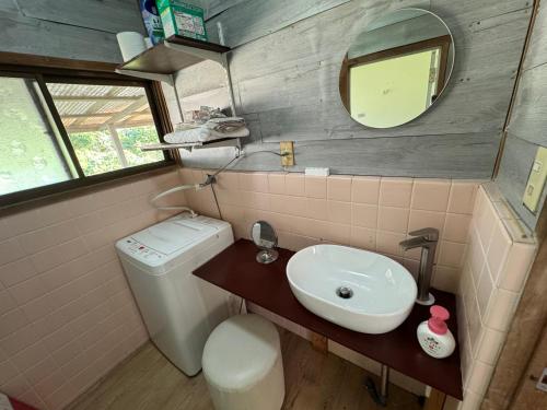 a bathroom with a sink and a toilet and a mirror at 民泊大浦崎荘 in Kure
