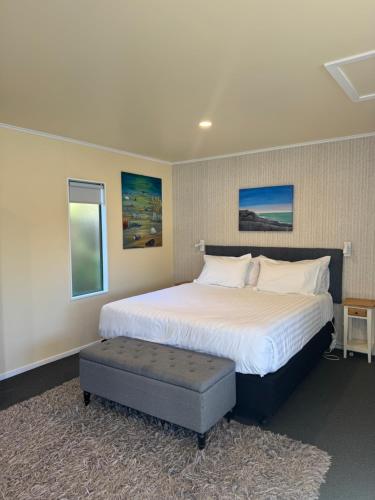 a bedroom with a large bed and a ottoman at Bay Cottages in Kaikoura