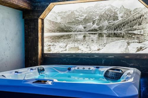 a bath tub in a room with a large window at A large mountain-style house with a spa area in Murzasichle