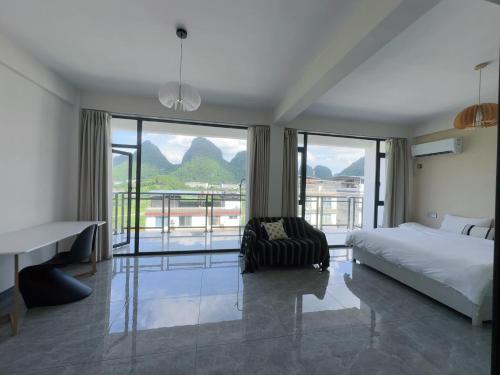 a bedroom with a bed and a balcony with mountains at shadow climers guest house in Yangshuo