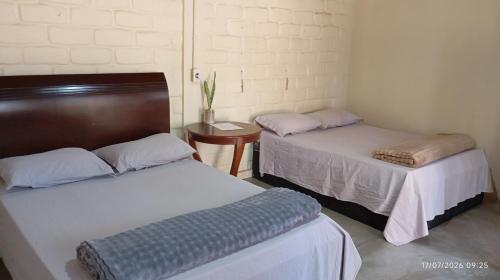 a room with two beds and a table at Chalé Primavera in Cavalcante