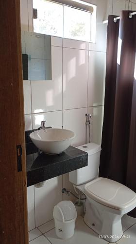 a white bathroom with a sink and a toilet at Chalé Primavera in Cavalcante