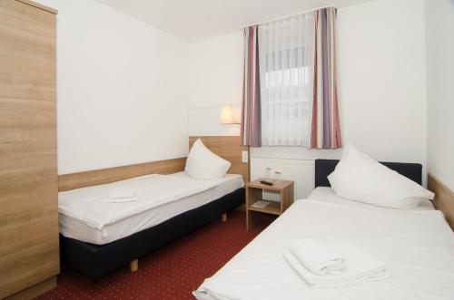 a hotel room with two beds and a window at Hotel -Restaurant Taormina in Birkenfeld