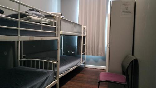 a bunk bed room with two bunk beds and a chair at 1849 Backpackers at The London in Albany