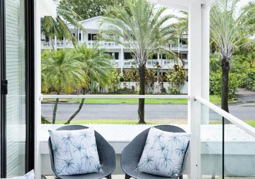 a porch with two chairs and palm trees at Beachfront Terraces with Onsite Reception & Check In in Port Douglas