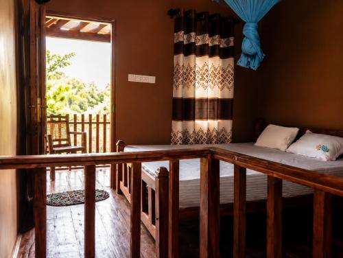 a room with a bed and a balcony with a window at Sinharaja Forest Lodge - Deniyaya in Dombagoda