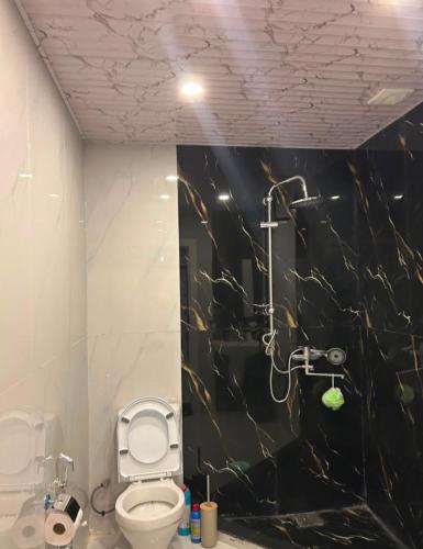 a bathroom with a toilet and a black marble wall at Rewad villa in Gabala