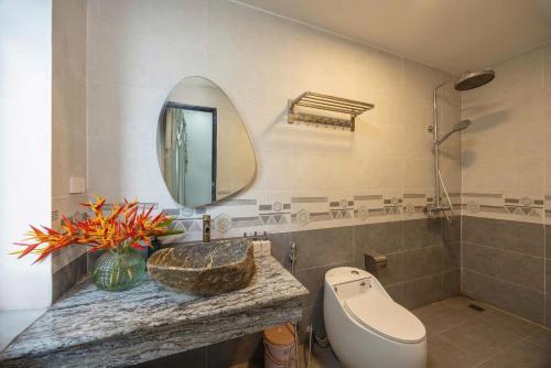 a bathroom with a sink and a toilet and a mirror at Sunstone Villa in Trung Gia