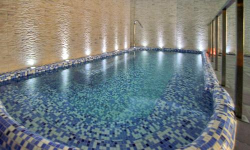 a large swimming pool with blue tiles in a building at Hotel Granada Palace, Affiliated by Melia in Monachil