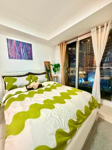 a bedroom with a green and white bed with a window at Affordable Staycation at Azure Urban Resort Residences Near NAIA in Manila