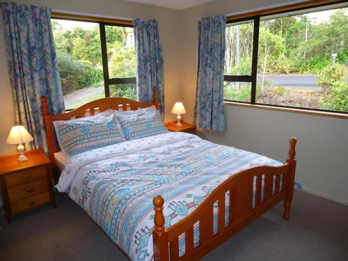 a bedroom with a bed and two windows at Wakari Holiday Home in Dunedin