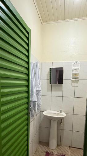 a bathroom with a sink and a green sliding door at Cantinho aconchego 2 in Naviraí