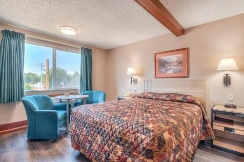 a hotel room with a bed and chairs and a window at Redmond Inn in Redmond