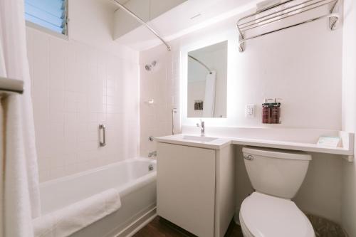 ein weißes Badezimmer mit Toilette, Waschbecken und Badewanne in der Unterkunft SCP Hilo Hotel in Hilo