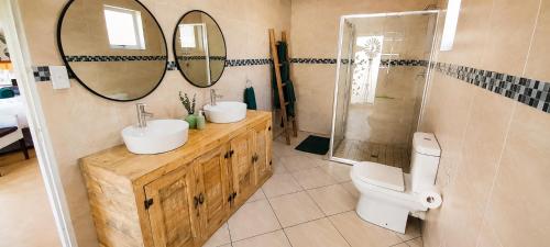 a bathroom with two sinks and a toilet and mirrors at Joy Haven - Open Plan Studio in Centurion