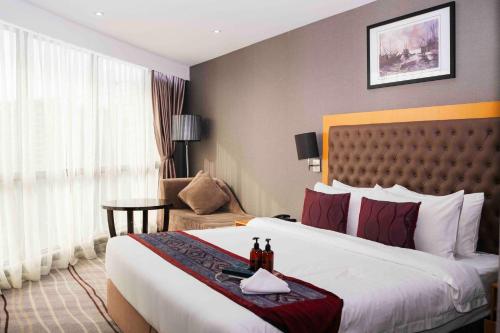 a hotel room with a large bed and a chair at Ming Garden Hotel in Kota Kinabalu
