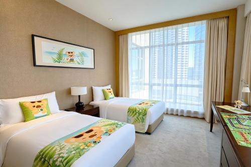 a hotel room with two beds and a window at Somerset Grand Central Dalian in Dalian