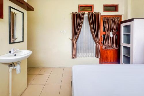 a bathroom with a sink and a toilet and a mirror at Kings Hotel Dieng RedPartner in Diyeng