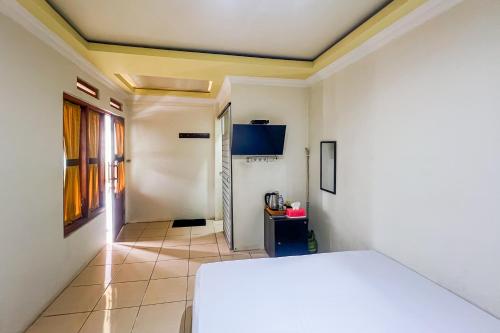 a room with a white bed and a hallway at Kings Hotel Dieng RedPartner in Diyeng