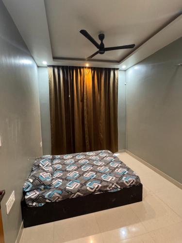 a bedroom with a bed and a ceiling fan at Sunita Kunj in Jhūsi