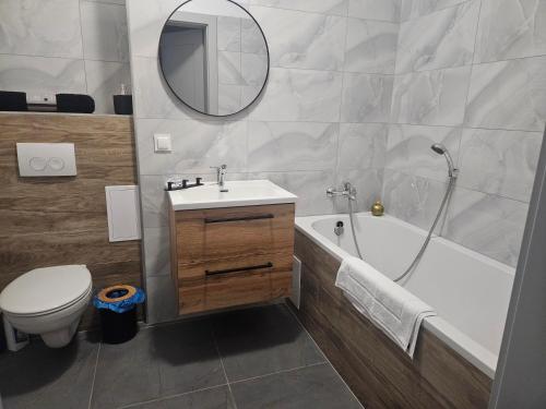 a bathroom with a sink and a tub and a toilet at Apartament Centrum in Giby